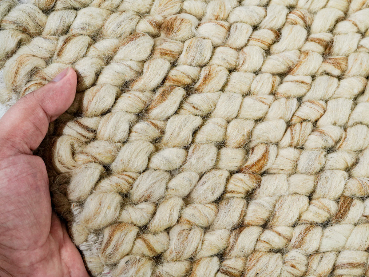 Beige Cashew Loop — Wool rug, hand holding the looped surface beside a corner