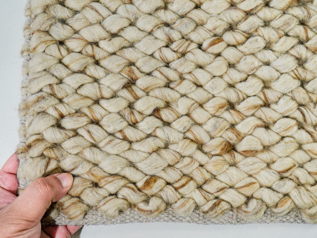 Beige Cashew Loop — Wool rug, hand supporting the lower edge beneath diagonal loop rows
