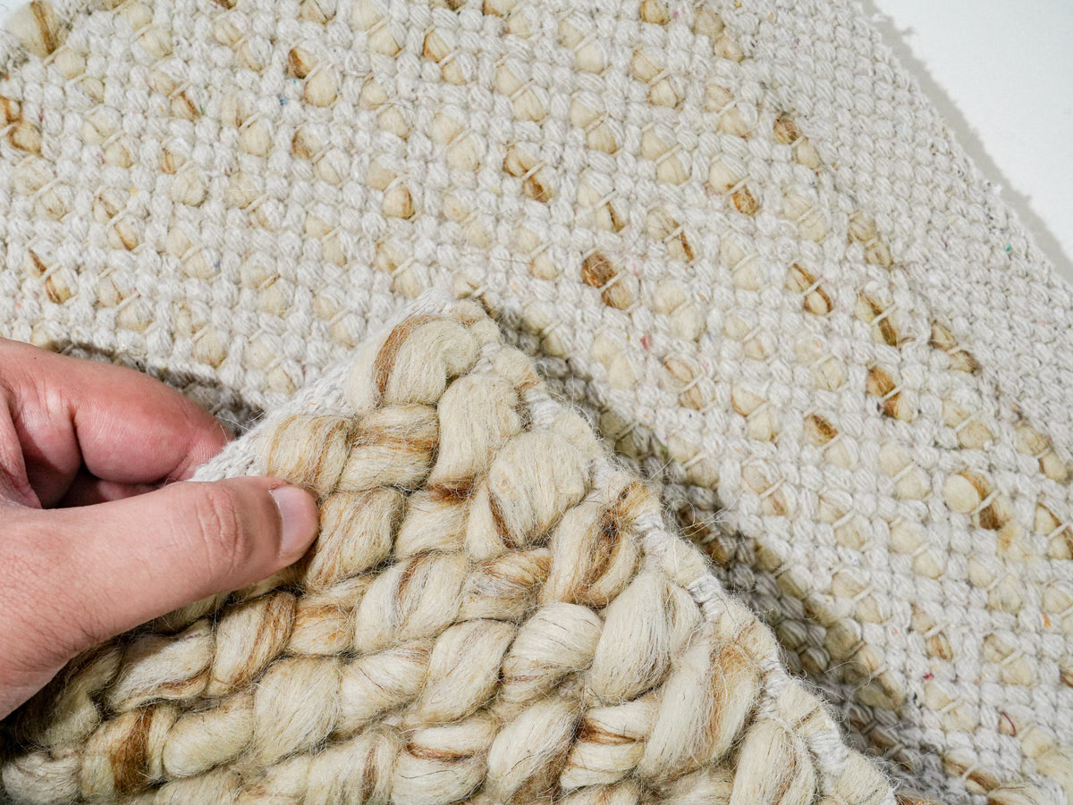 Beige Cashew Loop — Wool rug, folded corner revealing the chunky face against the underside