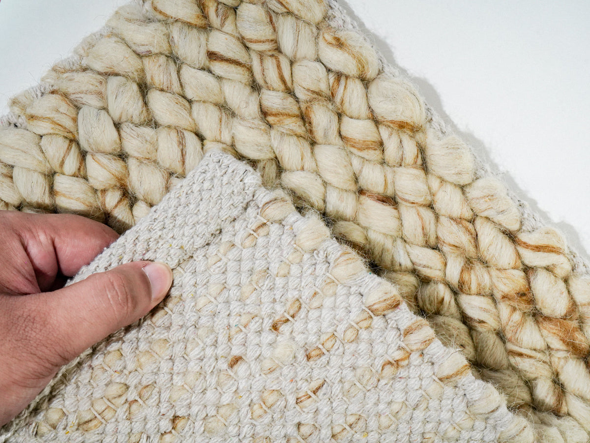 Beige Cashew Loop — Wool rug, hand lifting the underside in front of the looped face