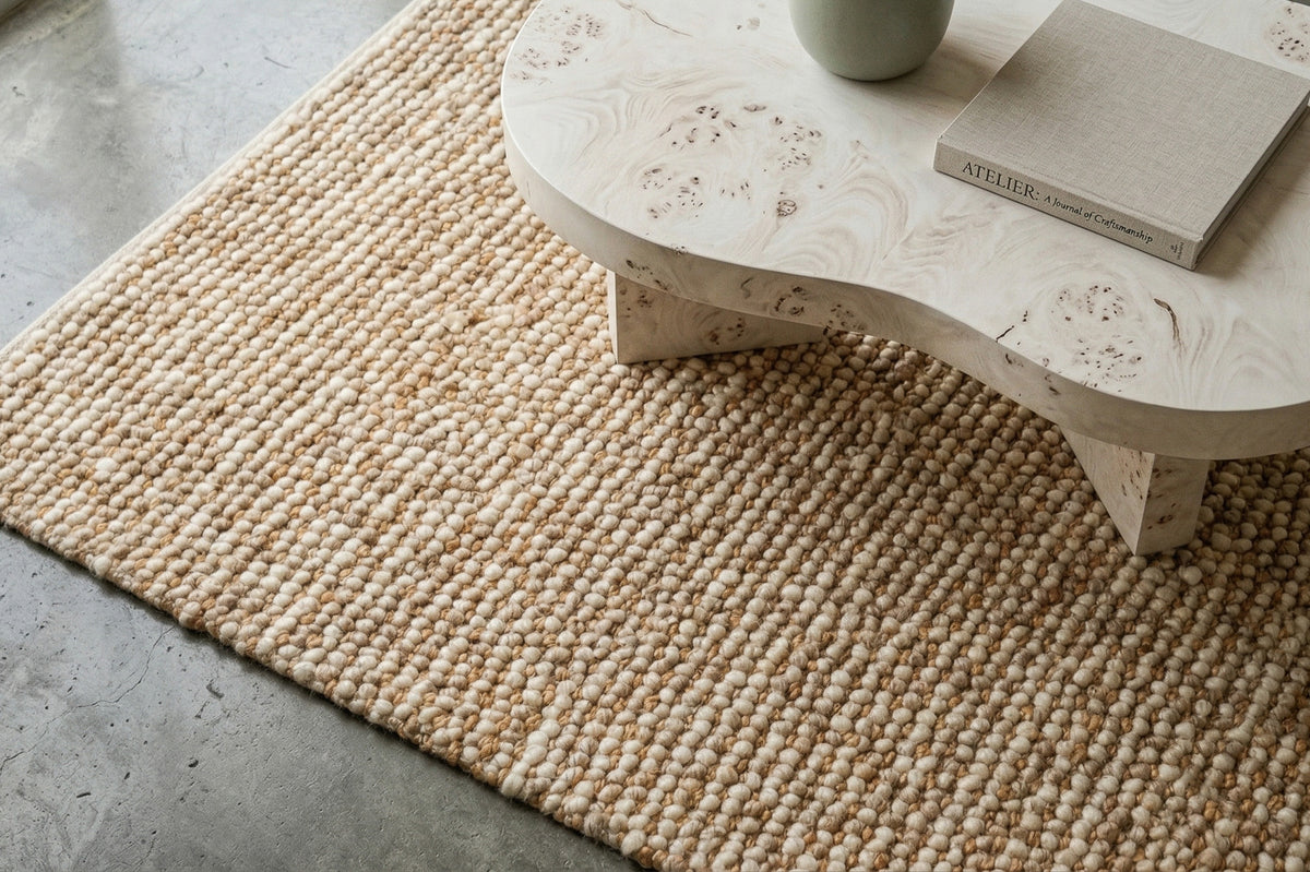 Loops With Jute — Beige Wool rug viewed diagonally beneath a curved coffee table on a gray floor