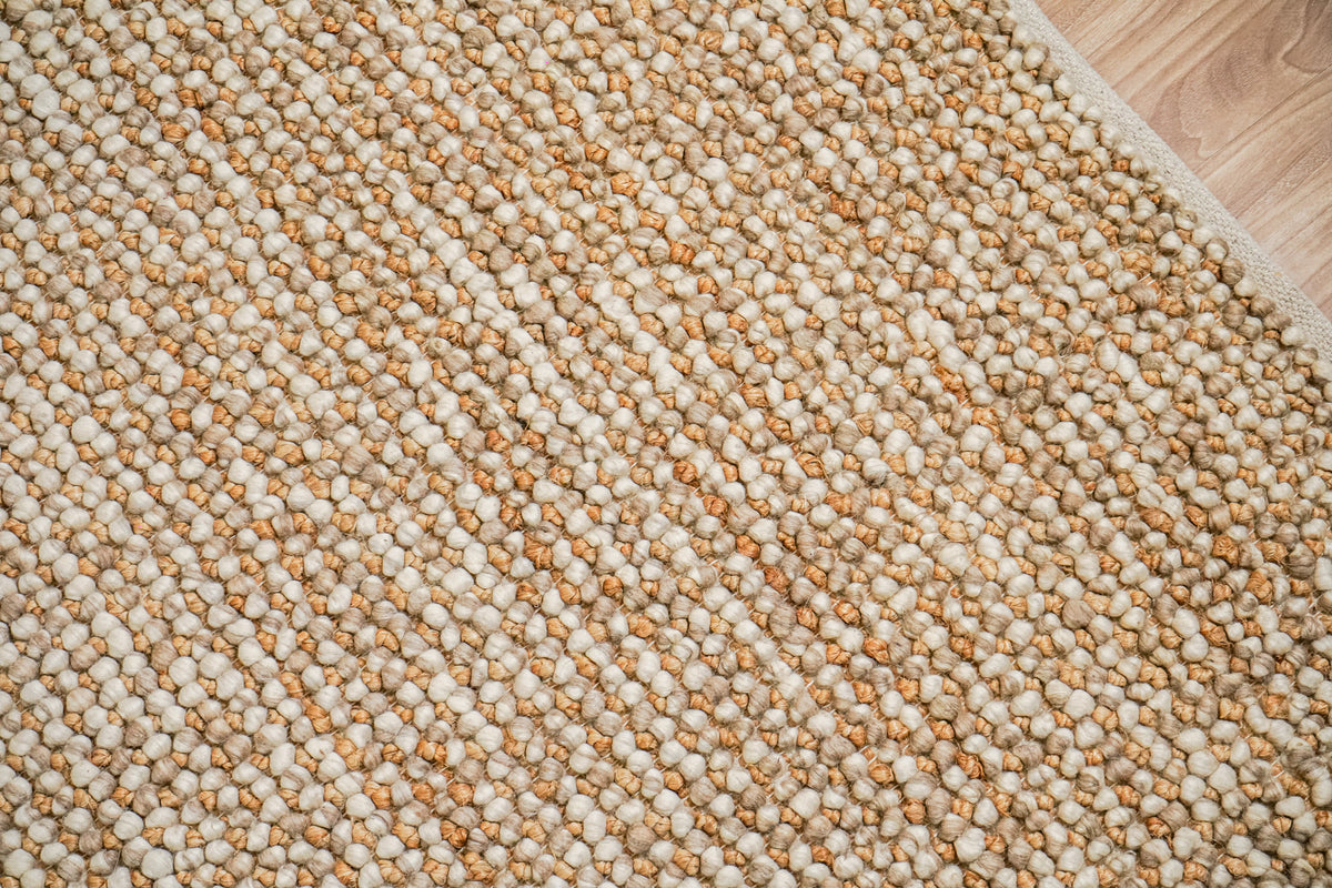 Loops With Jute — Beige Wool rug in a top-down texture detail showing rounded loops and the bound edge at upper right