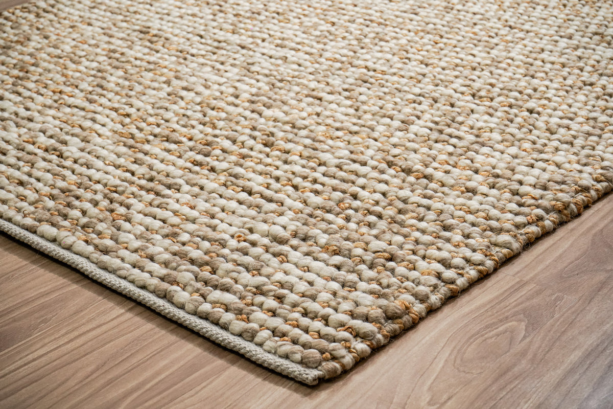 Loops With Jute — Beige Wool rug in a low angled view of the corner, loop texture and bound edge