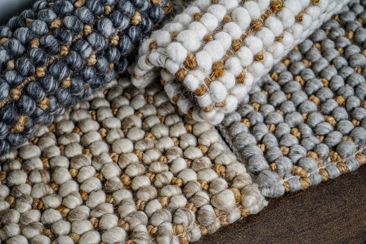 Loops With Jute — ivory wool rug sample second from the left in a fan of overlapping samples