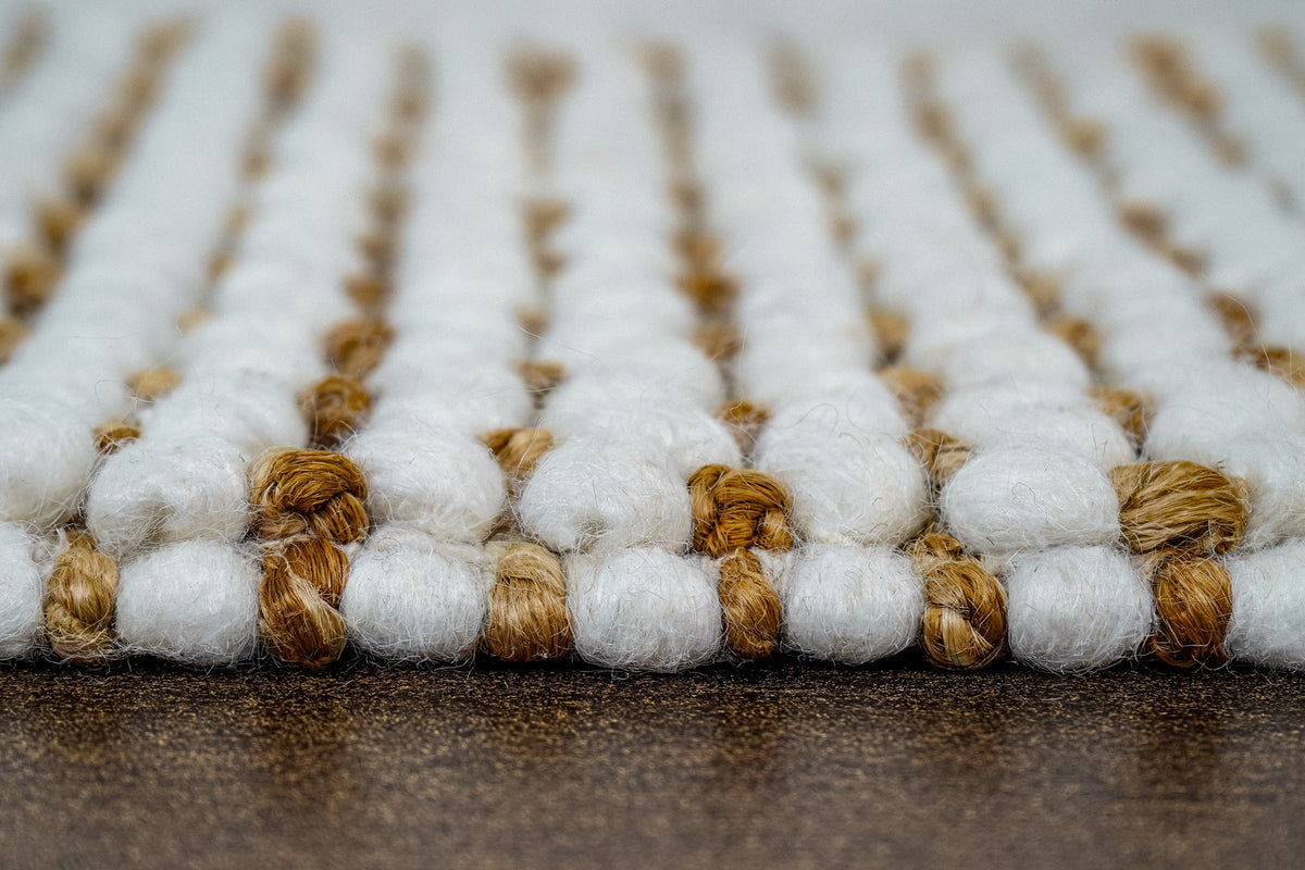 Loops With Jute — rolled ivory wool rug sample tied with twine across the foreground