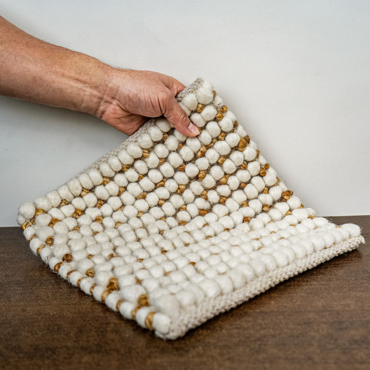 Loops With Jute — ivory wool rug sample lifted by hand to show its textured face and flexible drape