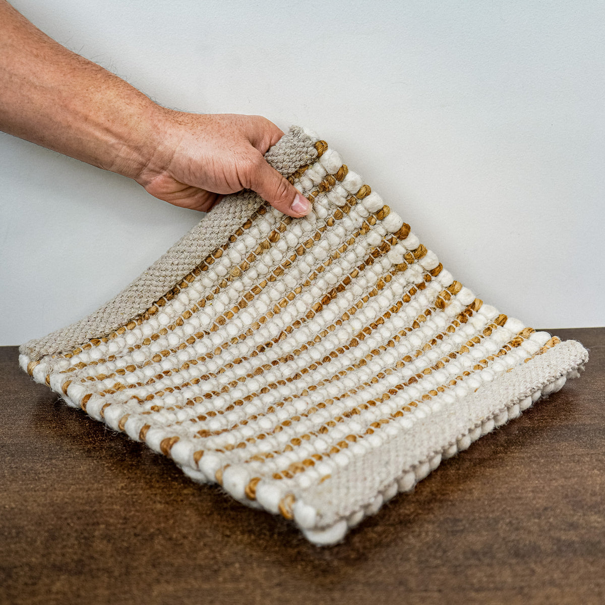 Loops With Jute — ivory wool rug sample viewed from above on a dark wood surface