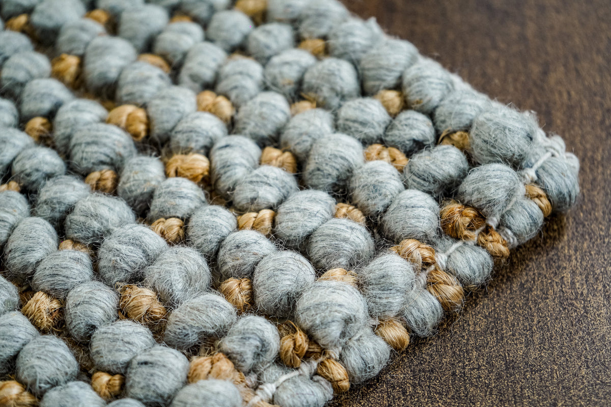 Loops With Jute — close-up of the gray wool rug's corner and rounded edge loops