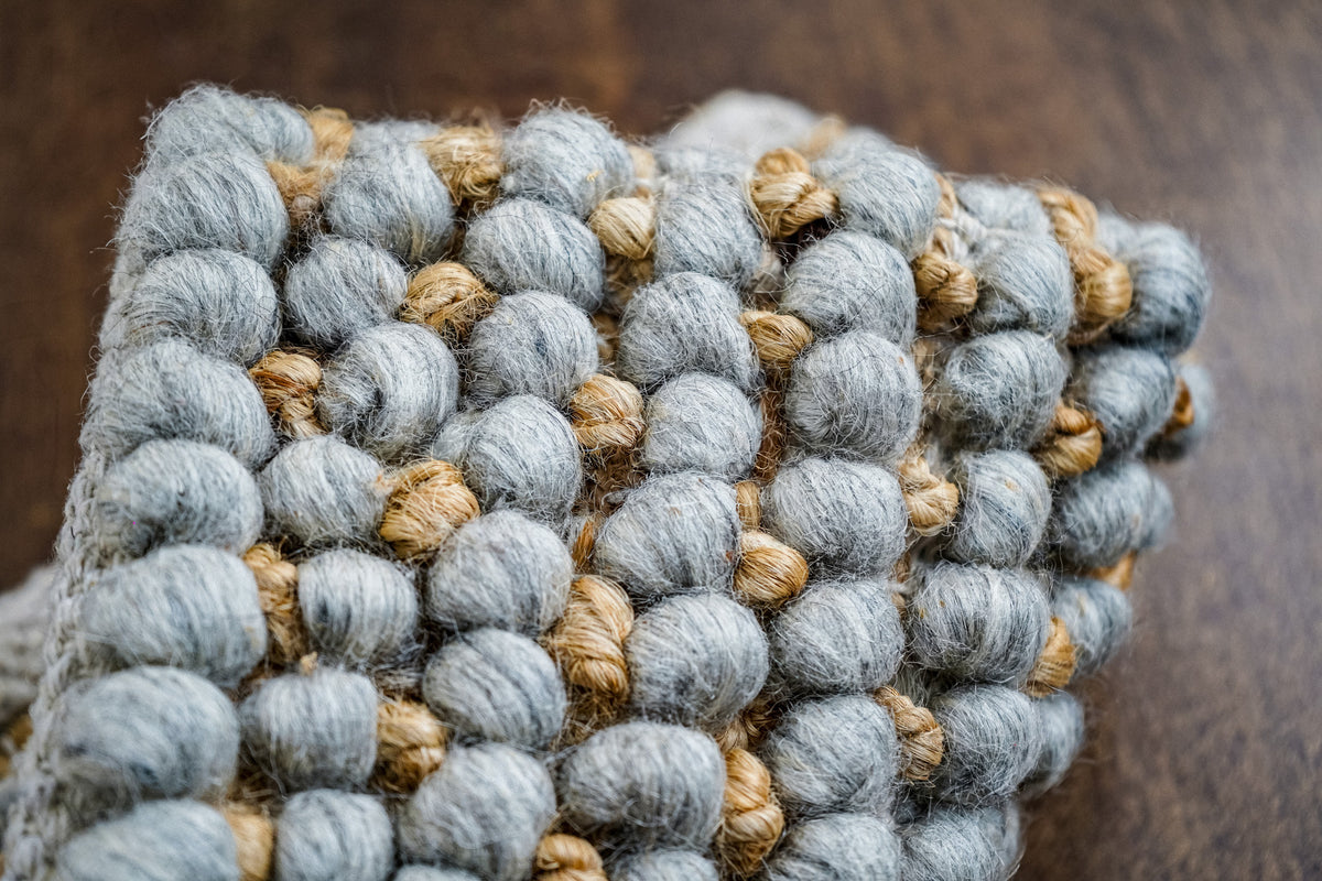 Loops With Jute — gray wool rug folded upward in a close-up of rounded loops