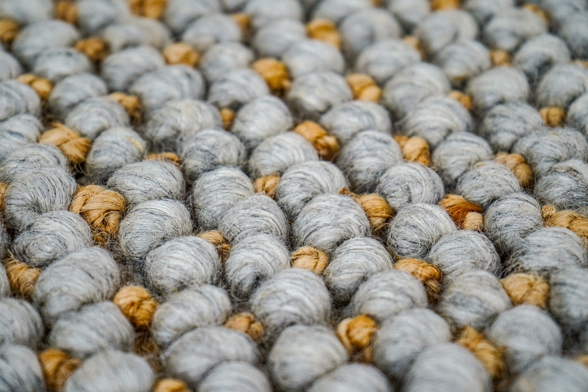 Loops With Jute — gray wool rug surface with rows of large loops and smaller golden-brown accents