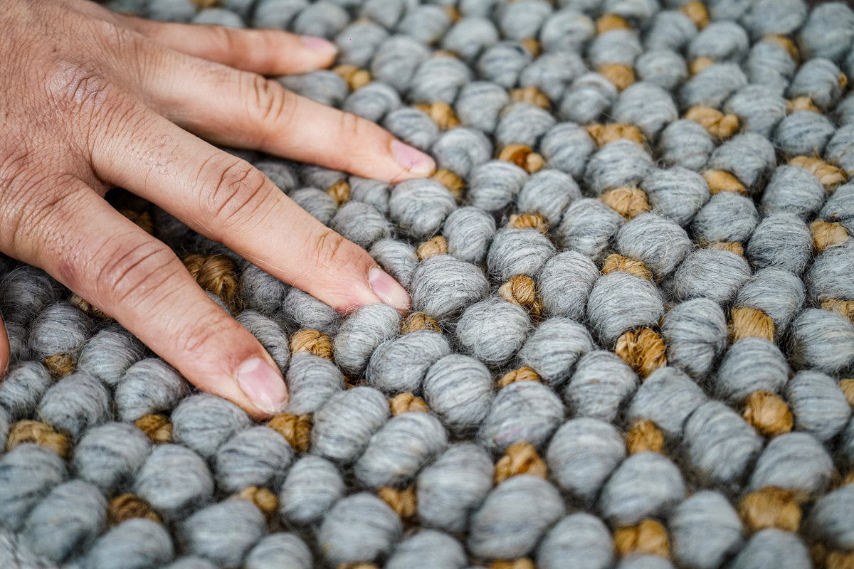 Loops With Jute — close-up of the gray wool rug's weave and loop pile beneath a spread hand