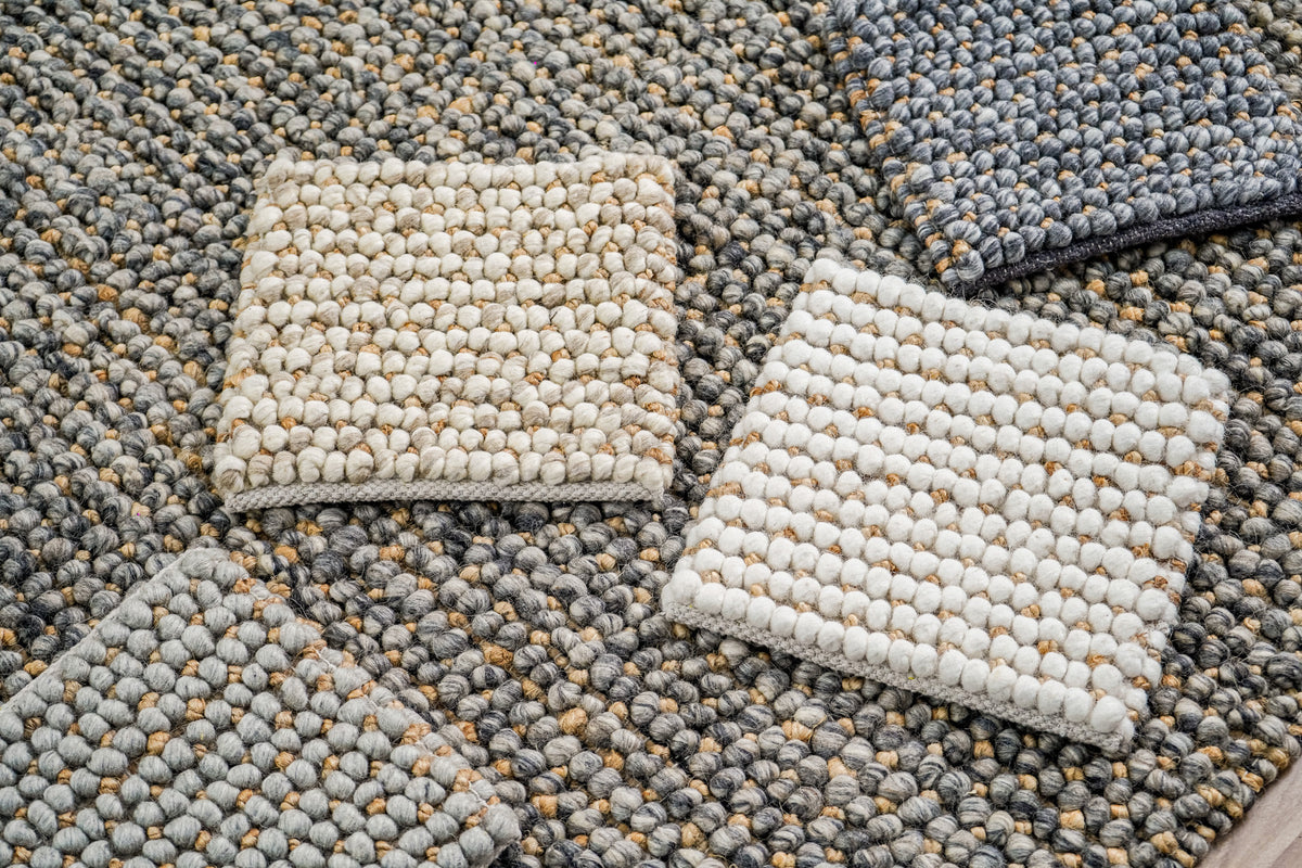Loops With Jute — gray wool rug sample partly visible at lower left among samples on a textured rug