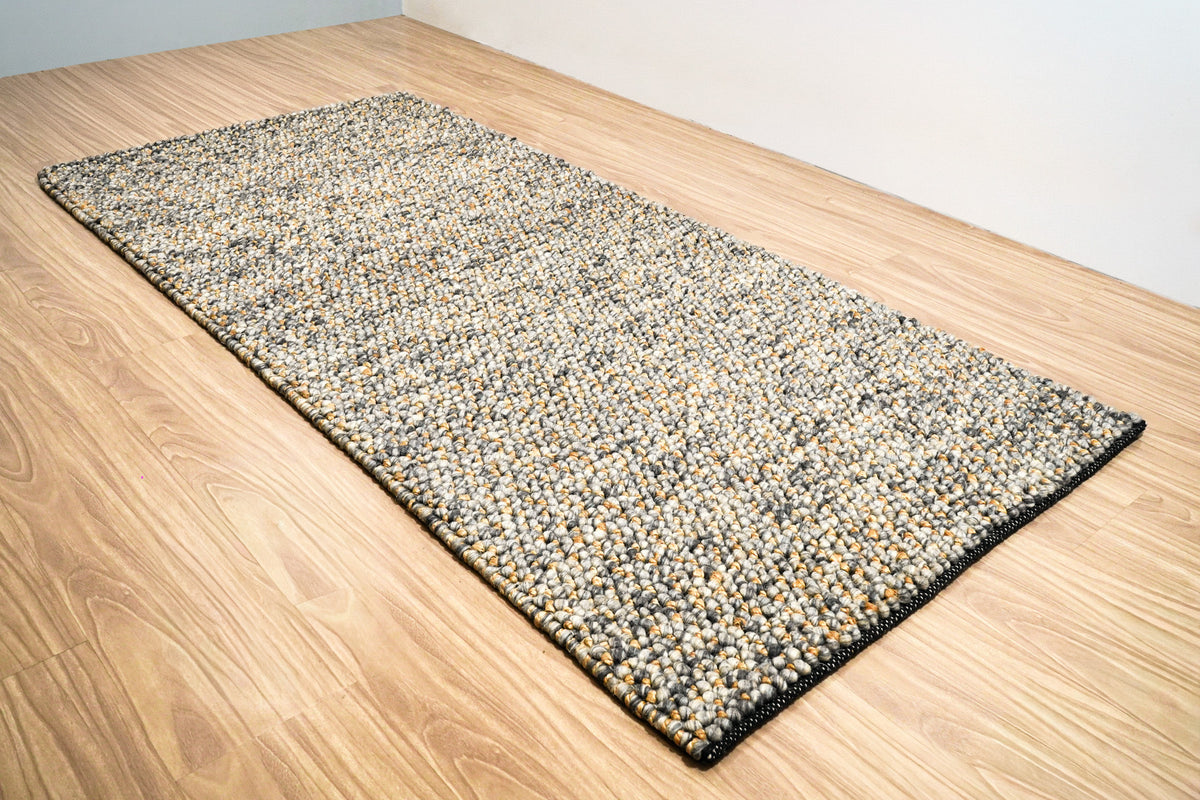 Loops With Jute — Gray Wool rug viewed lengthwise at an angle with the near corner in the foreground