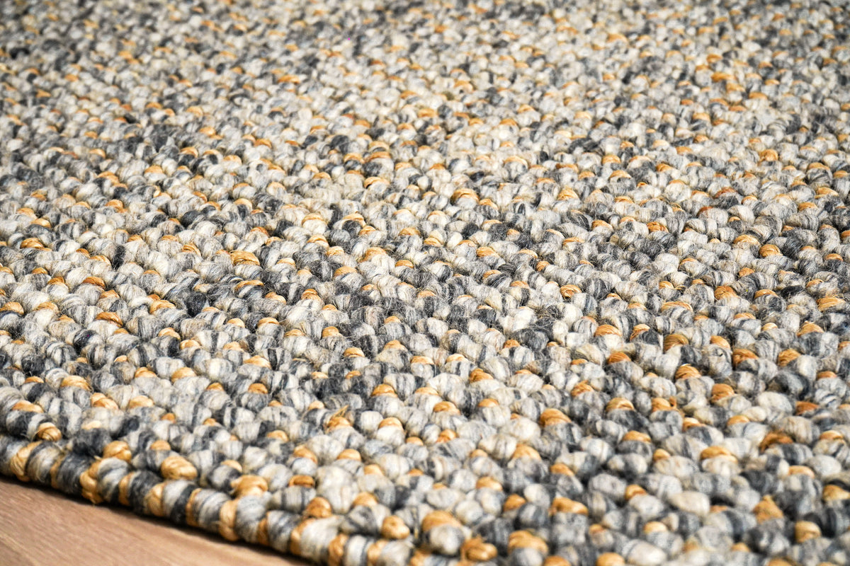 Loops With Jute — Gray Wool rug in a low angled close-up of the surface and front edge on wood flooring