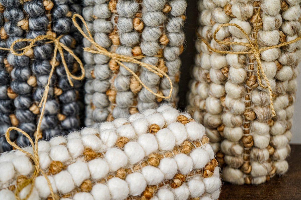 Loops With Jute — gray wool rug sample rolled upright at left and tied with twine