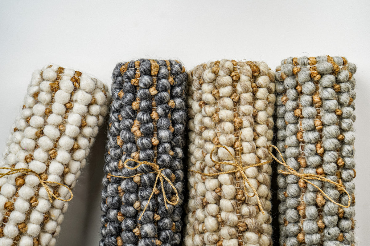 Loops With Jute — gray wool rug roll standing second from left beside an angled sample