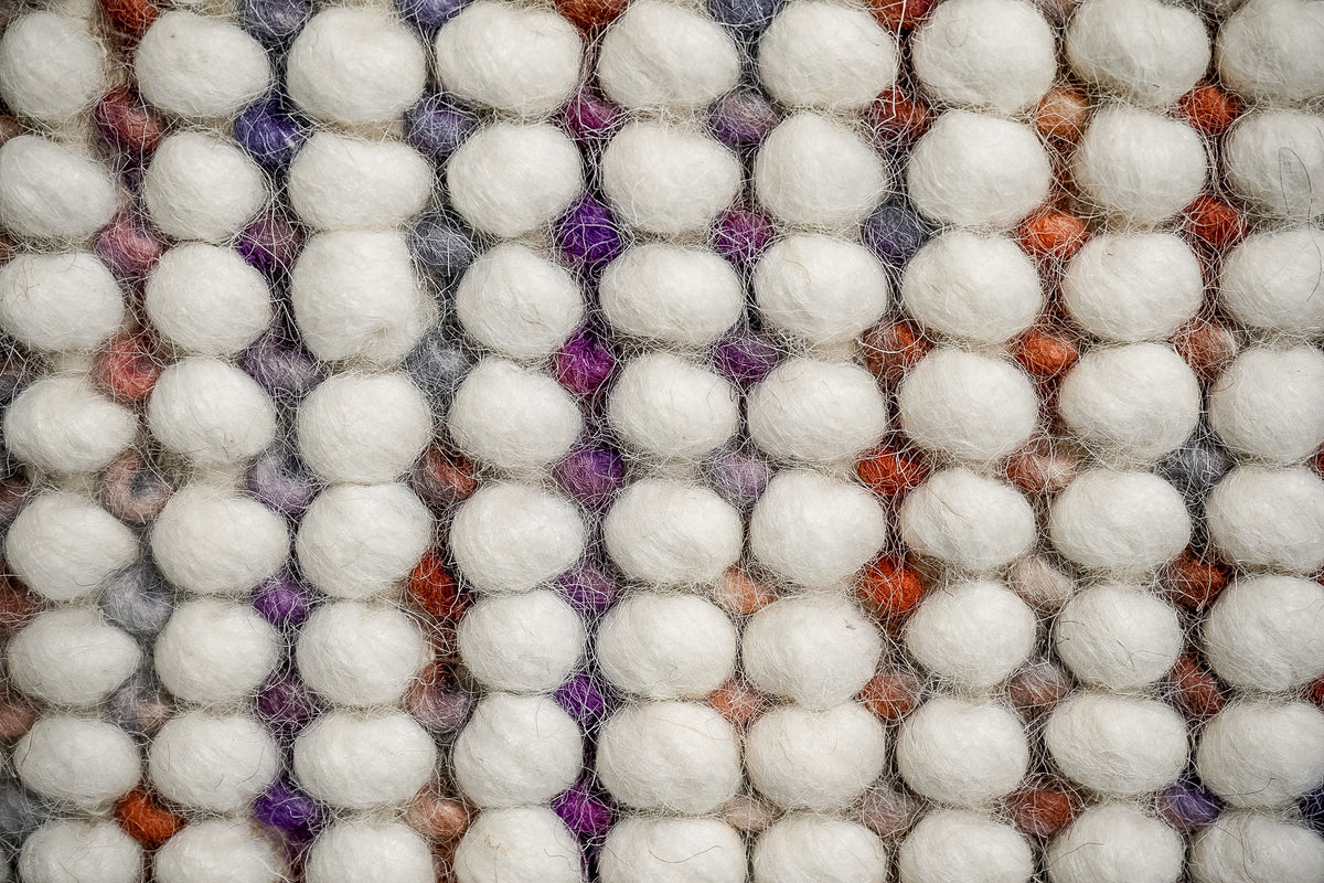 Alter Loops — Purple Wool rug in an extreme close-up of ivory loops with purple, gray and rust-colored details between rows