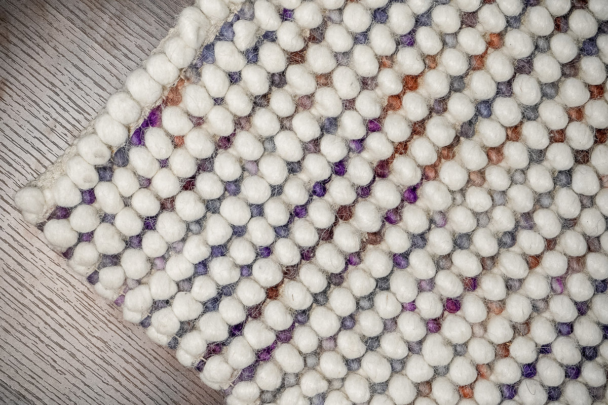 Alter Loops — Purple Wool rug corner viewed from above on gray-toned wood flooring
