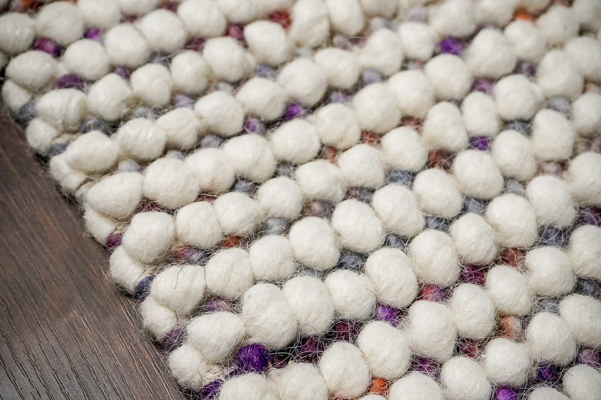 Alter Loops — Purple Wool rug in an angled surface close-up, showing ivory loops and smaller purple accents