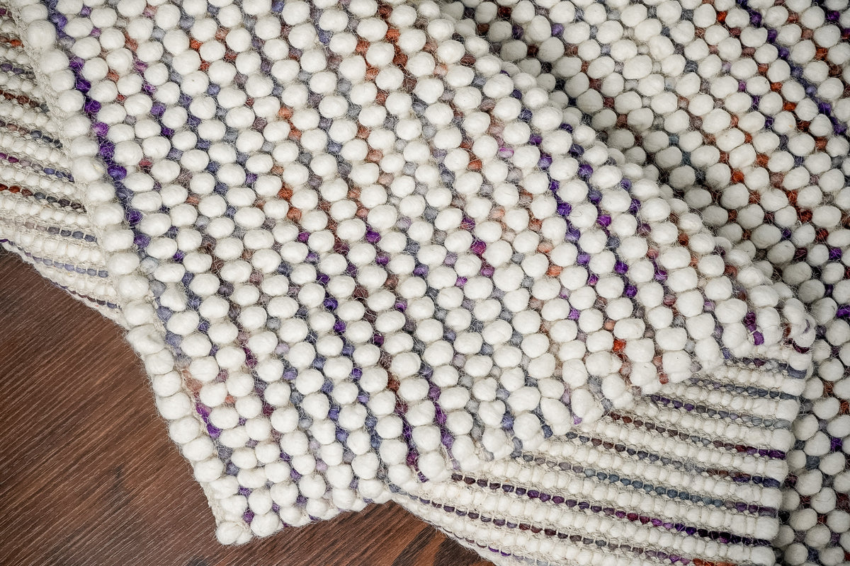 Alter Loops — close-up of the weave, pile and edge finish on the Purple Wool rug, with folded sections showing the striped…
