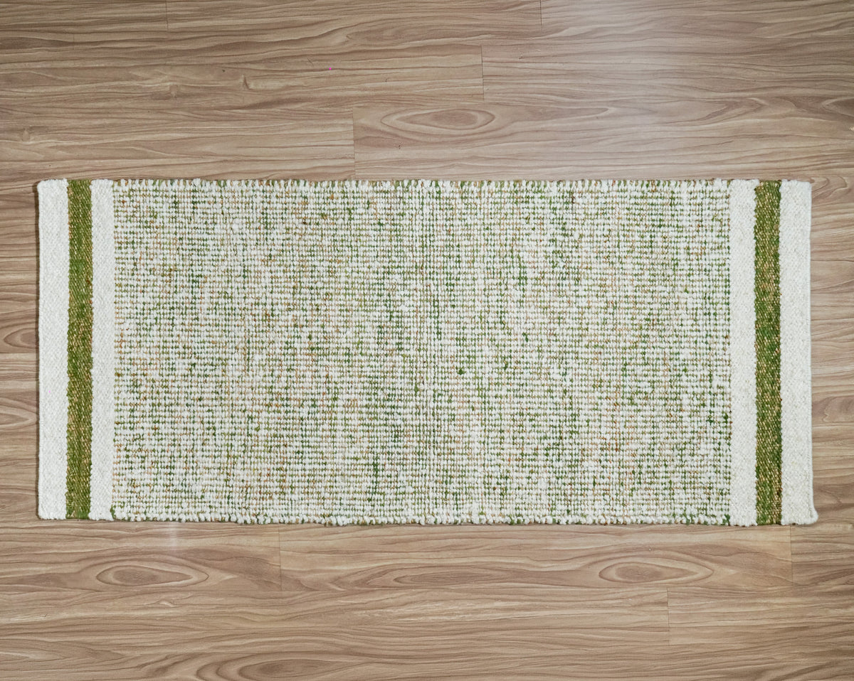 Green wool runner laid horizontally on a wood floor, with ivory bands and green stripes at both ends.