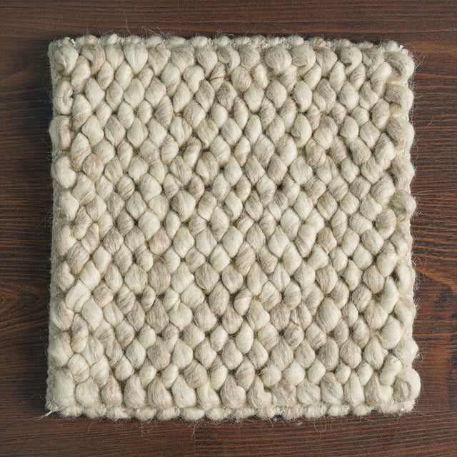 Beige chunky loop wool sample on a wooden surface