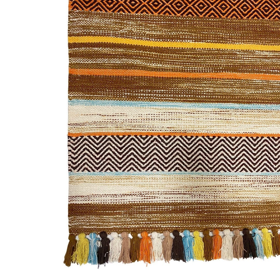 Full view of beige striped kilim rug on wood floor