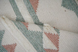 Pink blue kilim rug styled in a bedroom setting