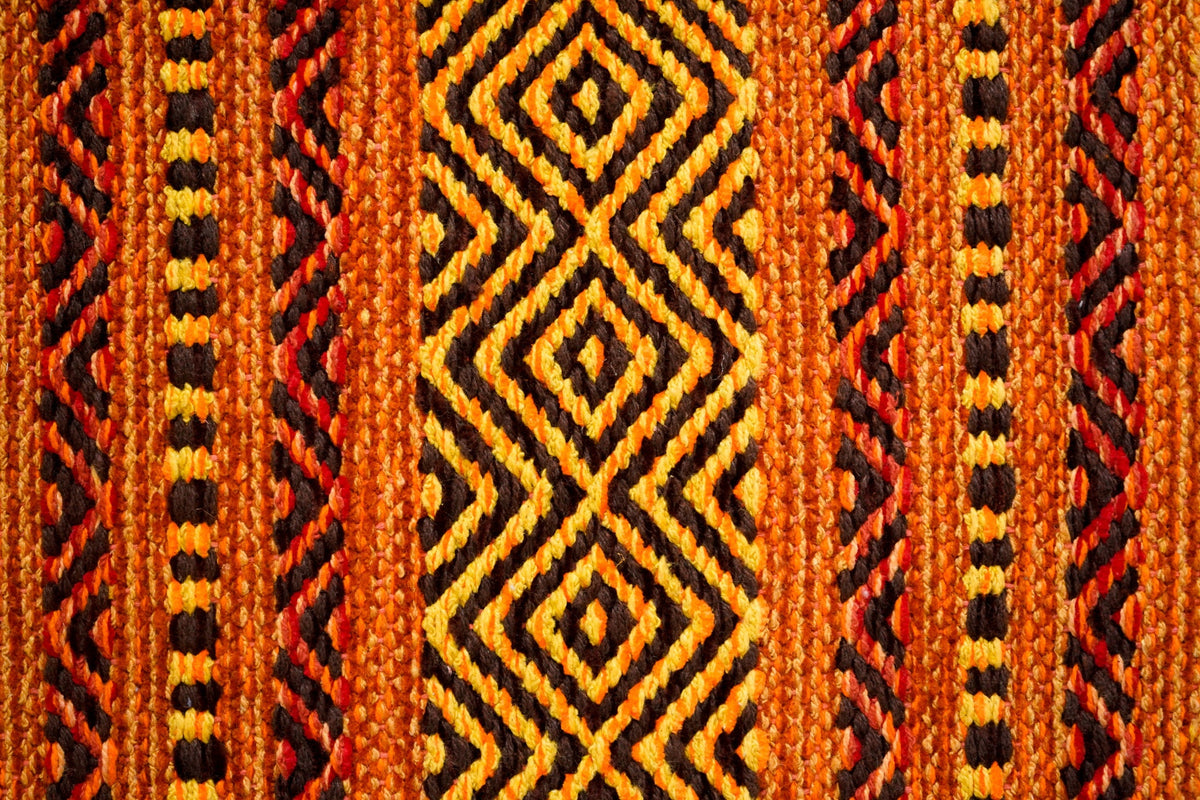 Orange kilim rug placed by bedside