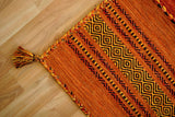 Full view of orange diamond pattern rug on floor