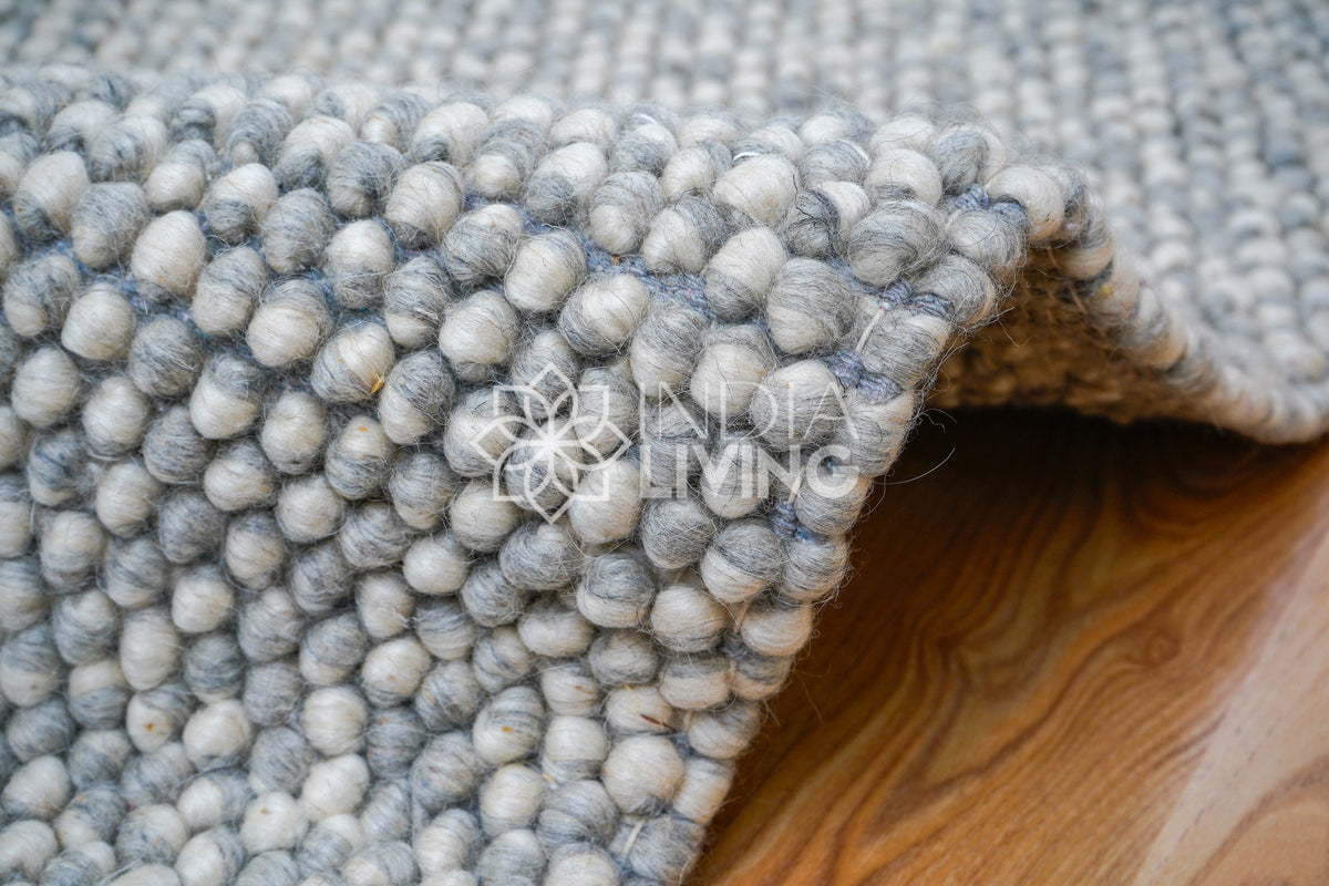 Grey wool rug placed in bedroom setting