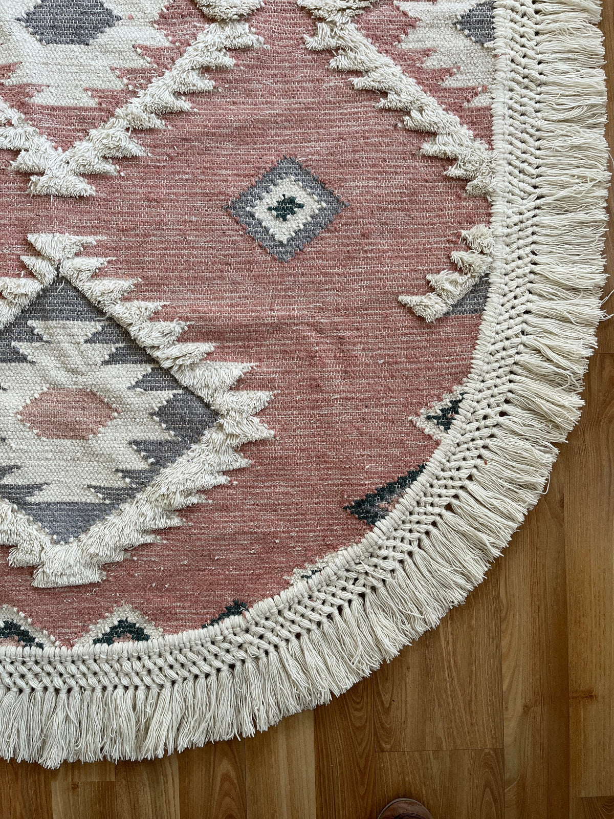 Full view of pink oval shaggy rug on wood floor