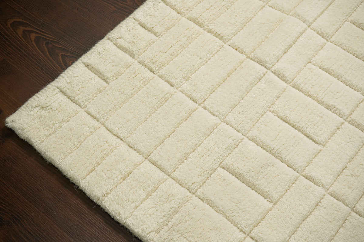 Minimalist wool rug under a bed in a bedroom