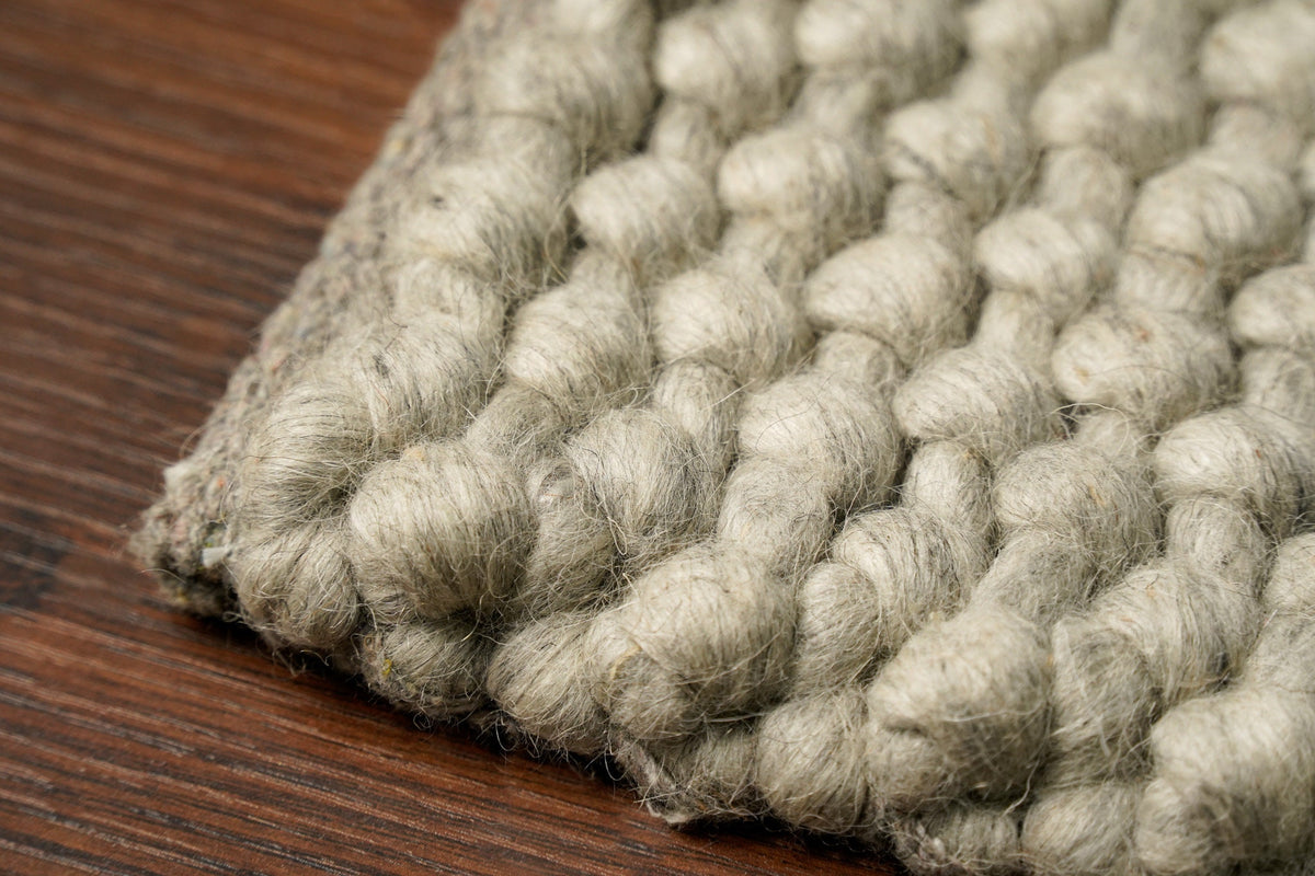 Grey wool rug pile texture close-up in natural light