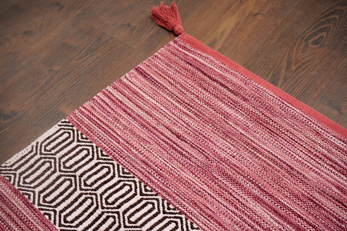 Full view of pink 8x10 kilim rug on wood floor