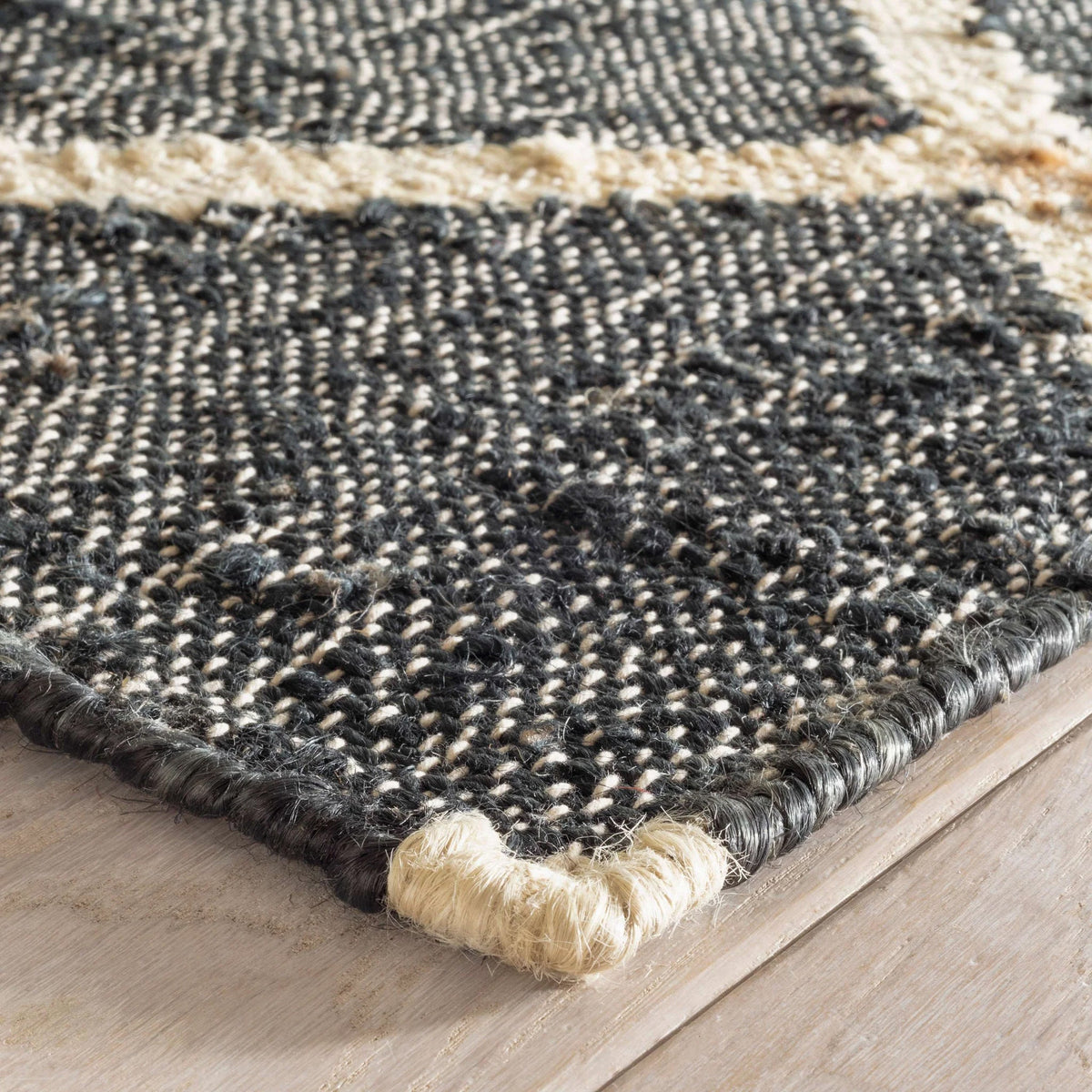 Black jute rug corner detail showing geometric pattern