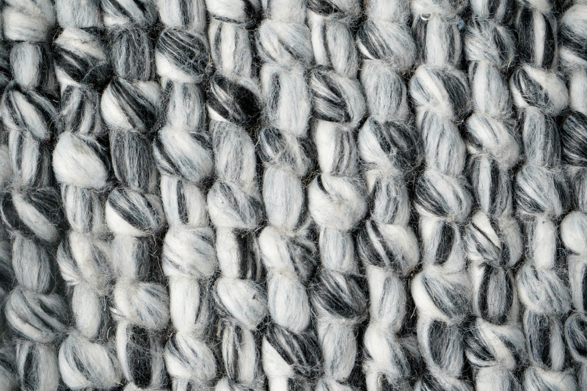 Grey mixture loop chunky wool rug in bedroom setting