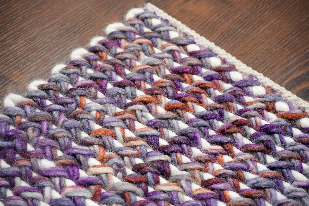 Purple wool rug styled in a bedroom