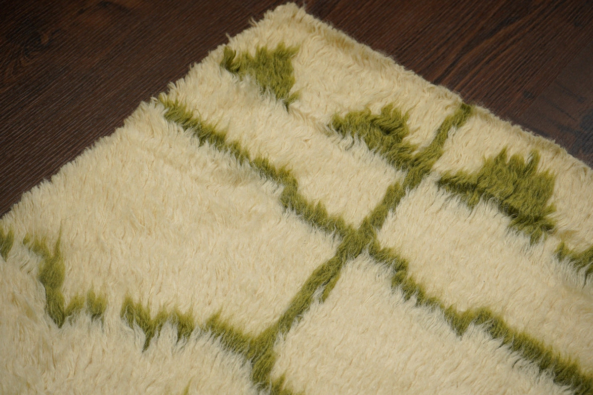 Tribal pattern detail on olive green wool rug