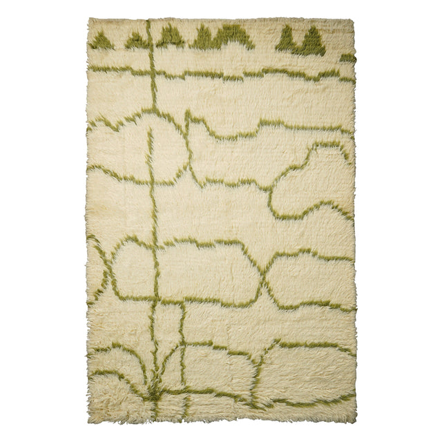 Green wool rug styled in a bohemian living room