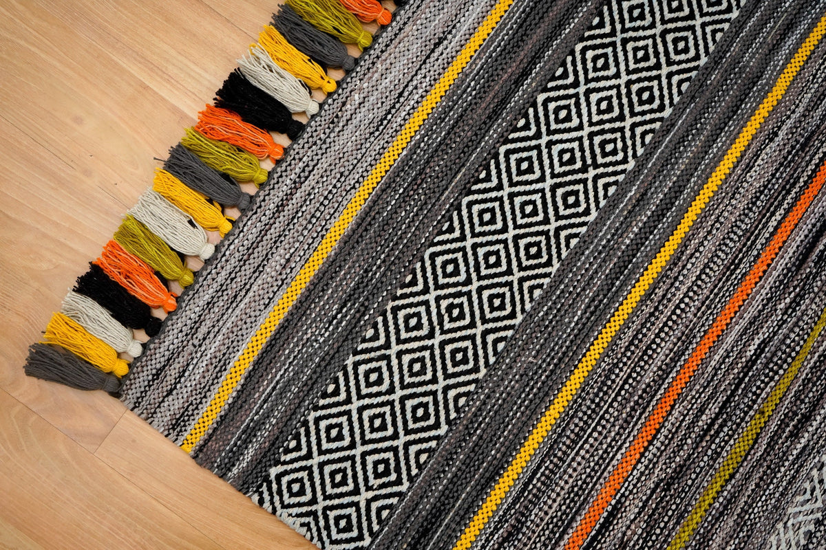 Pom-pom tassel detail on grey chenille rug