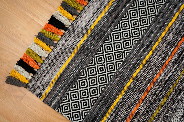 Pom-pom tassel detail on grey chenille rug