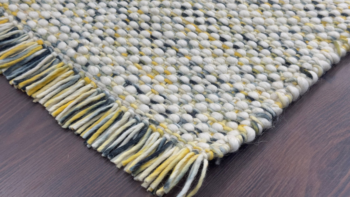 Full view of multi blend chunky wool rug on wood floor