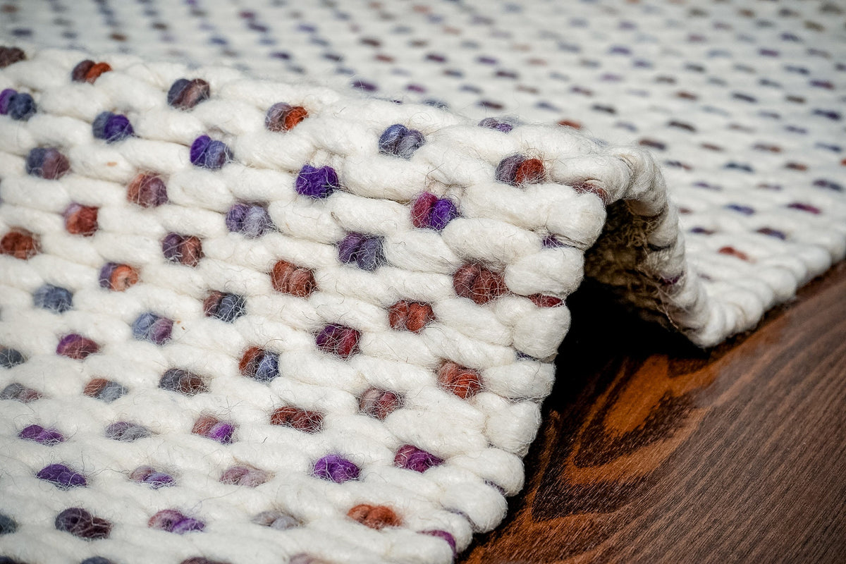 Close-up of chunky wool loop texture in ivory and purple