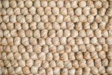 Beige wool rug styled in a bedroom
