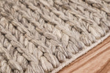 Taupe grey wool rug corner detail showing braided edge