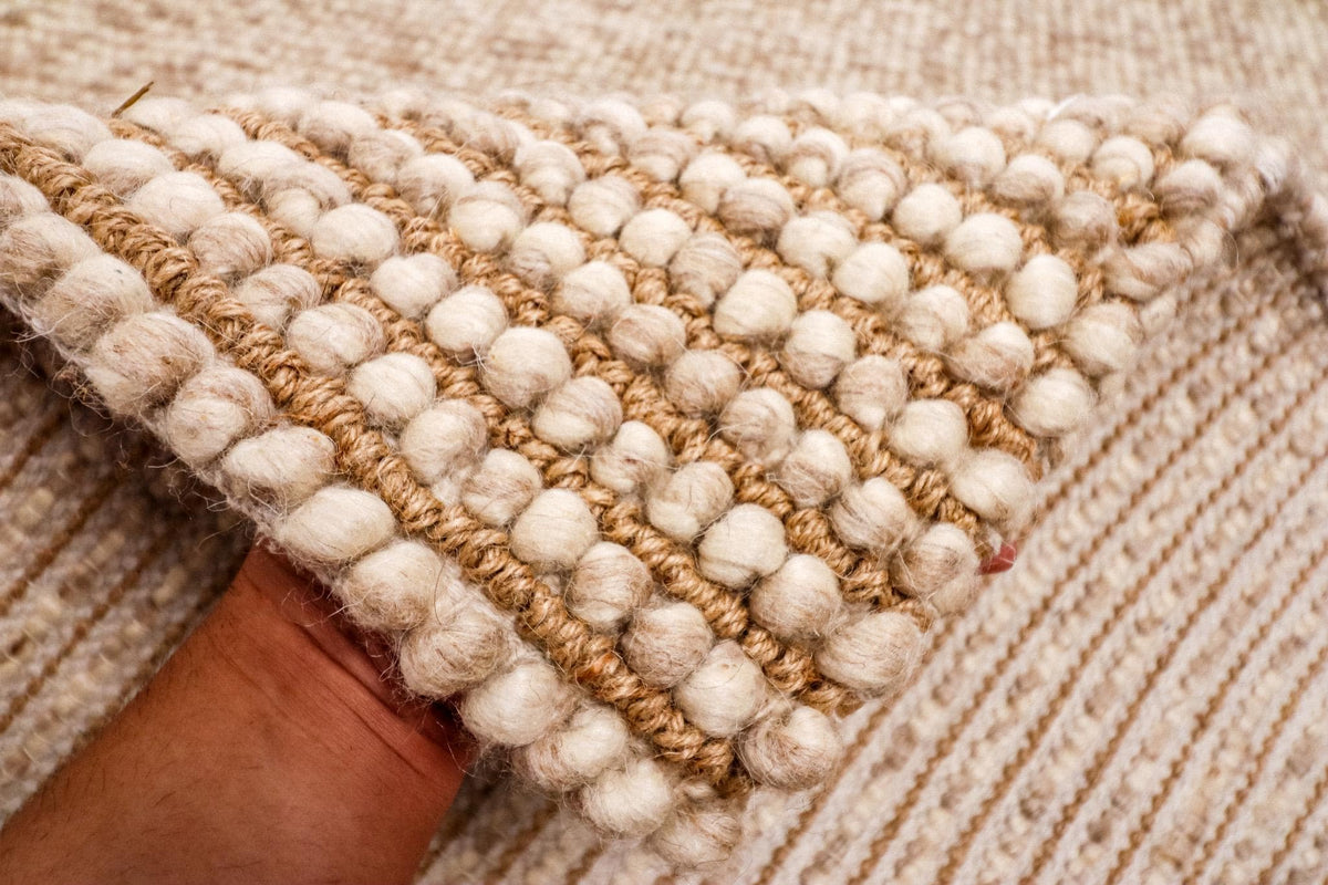 Taupe wool rug styled in a bedroom