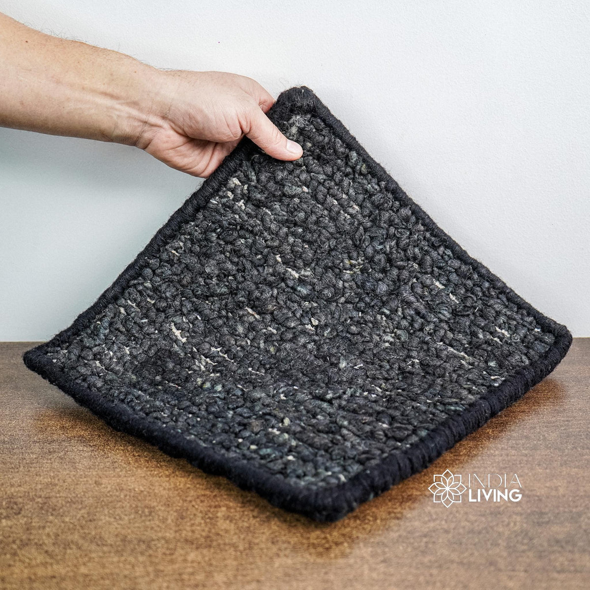Black wool rug rolled showing thickness