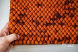 Close-up of felted thick pile wool texture in rust orange