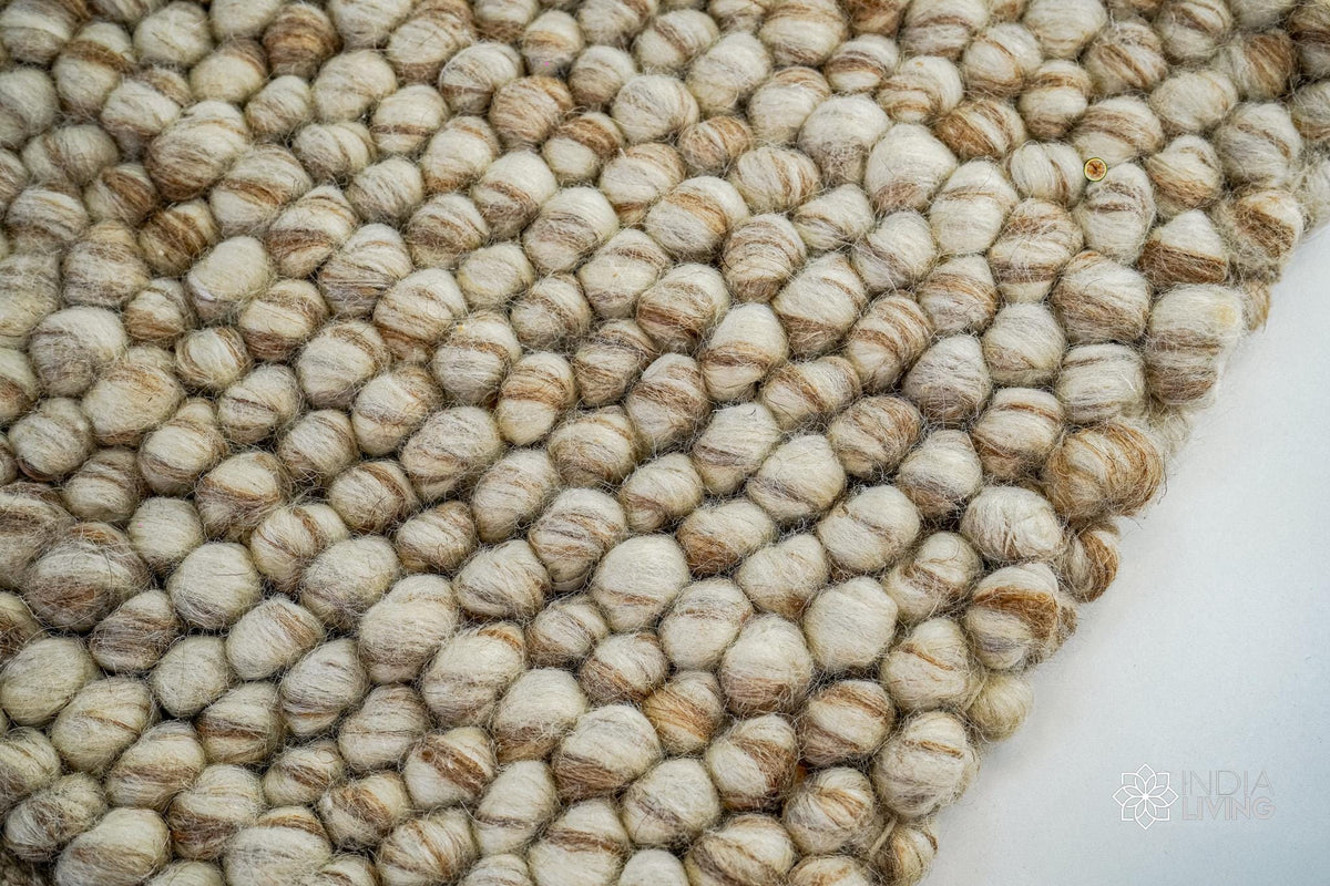 Corner detail of beige chunky pebble wool rug edge